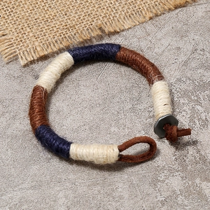 Handmade Bohemian woven fiber bracelet with leather button closure on stone background