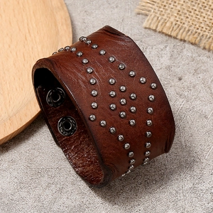 Detail view of brown leather punk bracelet featuring double-row metal studs and snap closure
