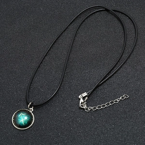 Close-up of luminous Sagittarius zodiac necklace with silver bezel and blue starry pendant