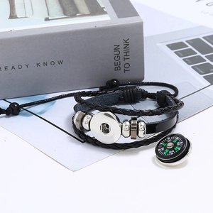 Detailed macro view of multilayer braided black leather bracelet with silver compass charm