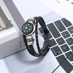 Detail van een gelaagde leren armband met kompas en zilverkleurige metalen kralen decoratie