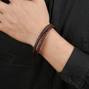 Men's brown double-layered braided leather bracelet on wrist with black polka dot shirt