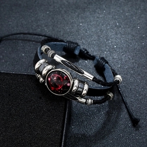 Macro shot of punk multilayer leather bracelet featuring a luminous constellation pendant