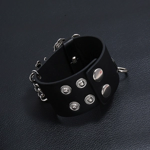 Detail eines Punk-Lederarmbands in Schwarz mit Silbernieten und Metallkettenelementen