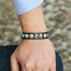 Close-up of punk black leather wristband with silver cone metal studs on male model
