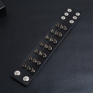 Detail of punk black leather bracelet featuring three rows of metallic cone spikes and snaps