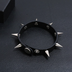 Macro detail of black punk leather bracelet featuring silver metal cone spikes and stud closure