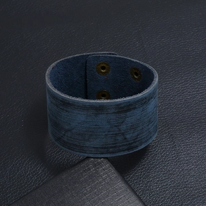 Détail du bracelet large en cuir bleu marine style punk avec boutons-pression bronze