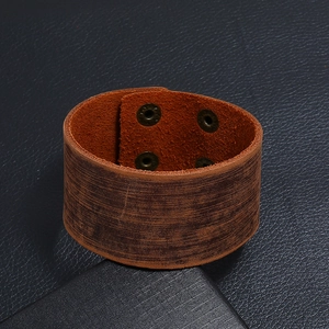 Détail macro d'un large bracelet en cuir marron rétro avec quatre boutons-pression cuivrés