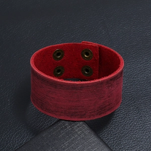 Gedetailleerde textuur van bordeauxrode brede leren armband met bronzen drukknopen