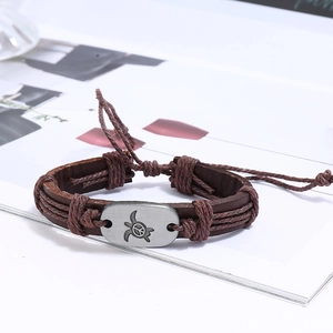 Detail of multi-layer leather bracelet featuring a turtle and peace symbol charm