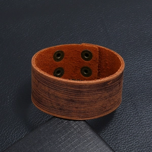 Detailopname van bruine vintage lederen brede armband met getextureerde bronzen knopen
