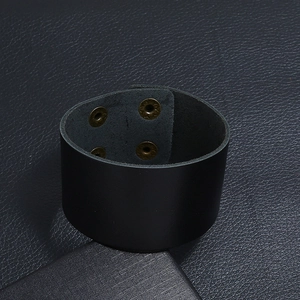 Détail du bracelet large en cuir noir avec deux boutons-pression en bronze vintage