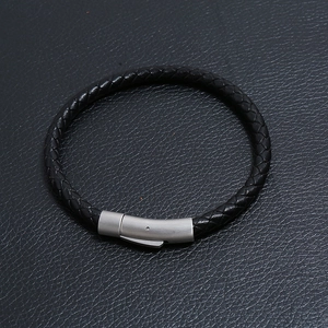 Dettaglio ravvicinato di un bracciale da uomo in pelle nera intrecciata con chiusura opaca