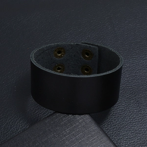 Detail van de brede zwarte lederen armband met vier vintage bronzen drukknopen