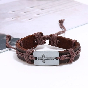 Detail of vintage brown leather bracelet with cross-engraved metal plate and woven cords
