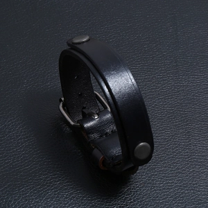 Détail macro du bracelet punk en cuir noir avec clous en métal gris et boucle
