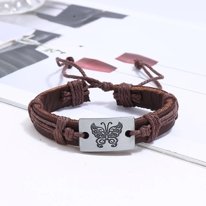 Close-up of braided leather bracelet featuring a silver metal plate with butterfly pattern