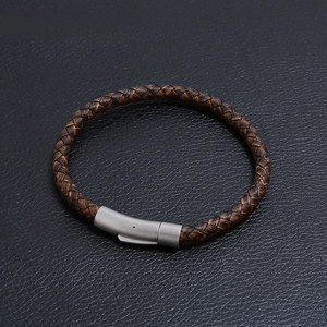 Dettaglio del bracciale in pelle intrecciata marrone scuro con chiusura in acciaio