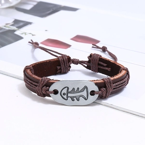 Close-up of multilayer braided leather bracelet with engraved silver fishbone charm