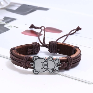Detail of layered brown leather bracelet with vintage silver bear charm and wax cord