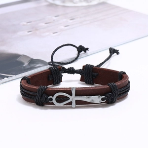 Detailed close-up of brown leather bracelet with silver Ankh charm and woven rope
