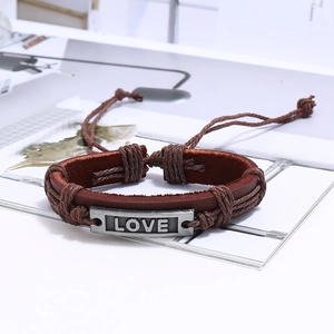 Détail du bracelet en cuir tressé multicouche avec plaque métallique gravée 'LOVE'