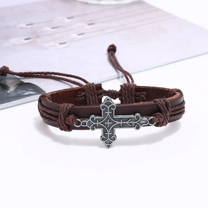 Detail of vintage braided leather bracelet featuring a silver cross charm and woven cords