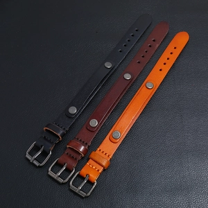 Détail de bracelets en cuir noir, marron et orange avec boucles métalliques et rivets décoratifs