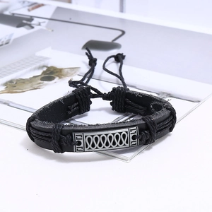 Détail d'un bracelet multicouche en cuir tressé noir avec plaque en alliage gravée vintage