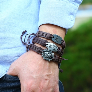 Detail of three-piece vintage braided leather bracelet set with lion and turtle metal charms