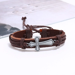 Detailed view of vintage brown leather bracelet with silver cross and braided rope cords