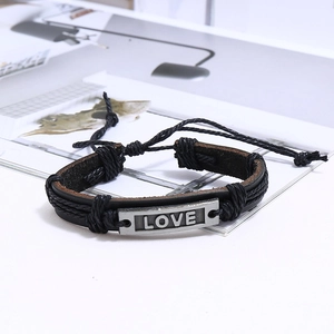 Gros plan détaillé d'un bracelet en cuir tressé avec plaque métallique gravée LOVE