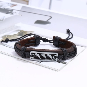 Détail d'un bracelet en cuir tissé main avec gravure de dauphin sur plaque en métal