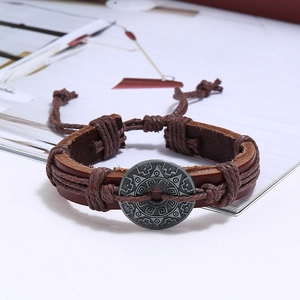 Close-up of vintage brown leather bracelet with ethnic style engraved metal plate