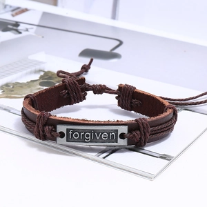 Gros plan du bracelet en cuir tressé multicouche avec plaque en métal gravée forgiven