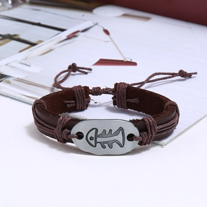 Detail showing vintage braided brown leather bracelet with an engraved metal fishbone charm