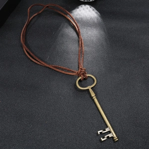 Vintage bronze key pendant necklace with dark brown leather cord on black background