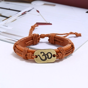 Detail of woven brown leather bracelet featuring a bronze Om symbol on an oval metal plate