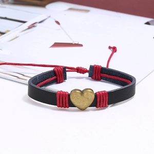 Détail d'un bracelet en cuir tressé avec breloque cœur et accents de cordon rouge