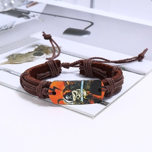 Macro shot of pirate skull charm on brown braided leather and wax cord bracelet