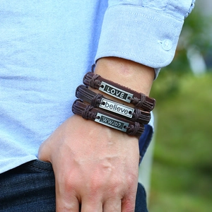 Détail de bracelets multicouches en cuir marron avec gravures LOVE et believe au poignet