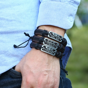 Gros plan de bracelets en cuir tressé pour hommes avec charms gravés Palau et Tobago