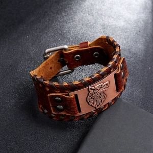 Macro detail of Nordic wolf head engraving on wide brown leather Viking bracelet for men