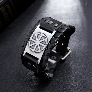 Detail of Slavic Kolovrat symbol on a braided black leather wristband with metal studs