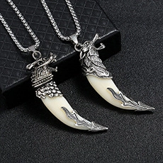Vue macro de deux colliers pour hommes avec pendentifs tête de loup et dent d'argent