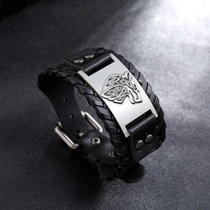 Close-up of Celtic wolf head emblem on leather bracelet with woven edges and metal studs