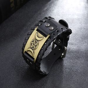 Détail macro du bracelet punk en cuir avec pentagramme en bronze et coutures tressées
