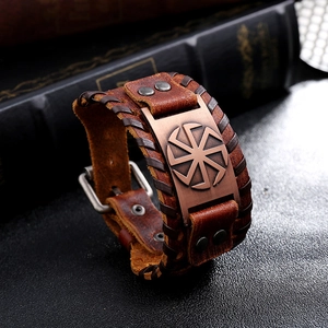 Macro detail of vintage brown leather bracelet with bronze sun wheel plaque and buckle