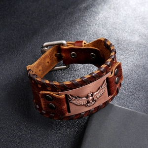 Dettaglio del bracciale in pelle vintage con incisione di aquila e bordi intrecciati